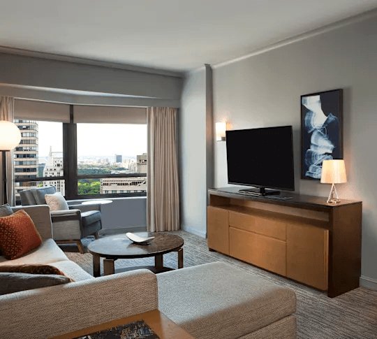 Spacious suite living room with sectional sofa, TV, and city view