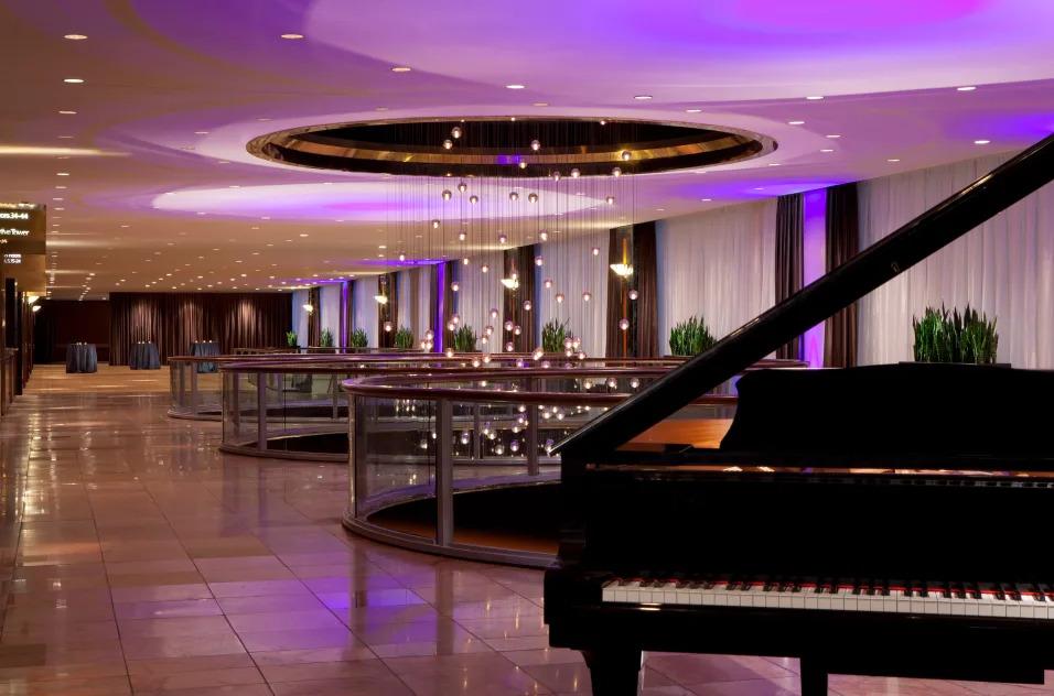 Elegant ballroom with purple lighting, grand piano, and open reception area