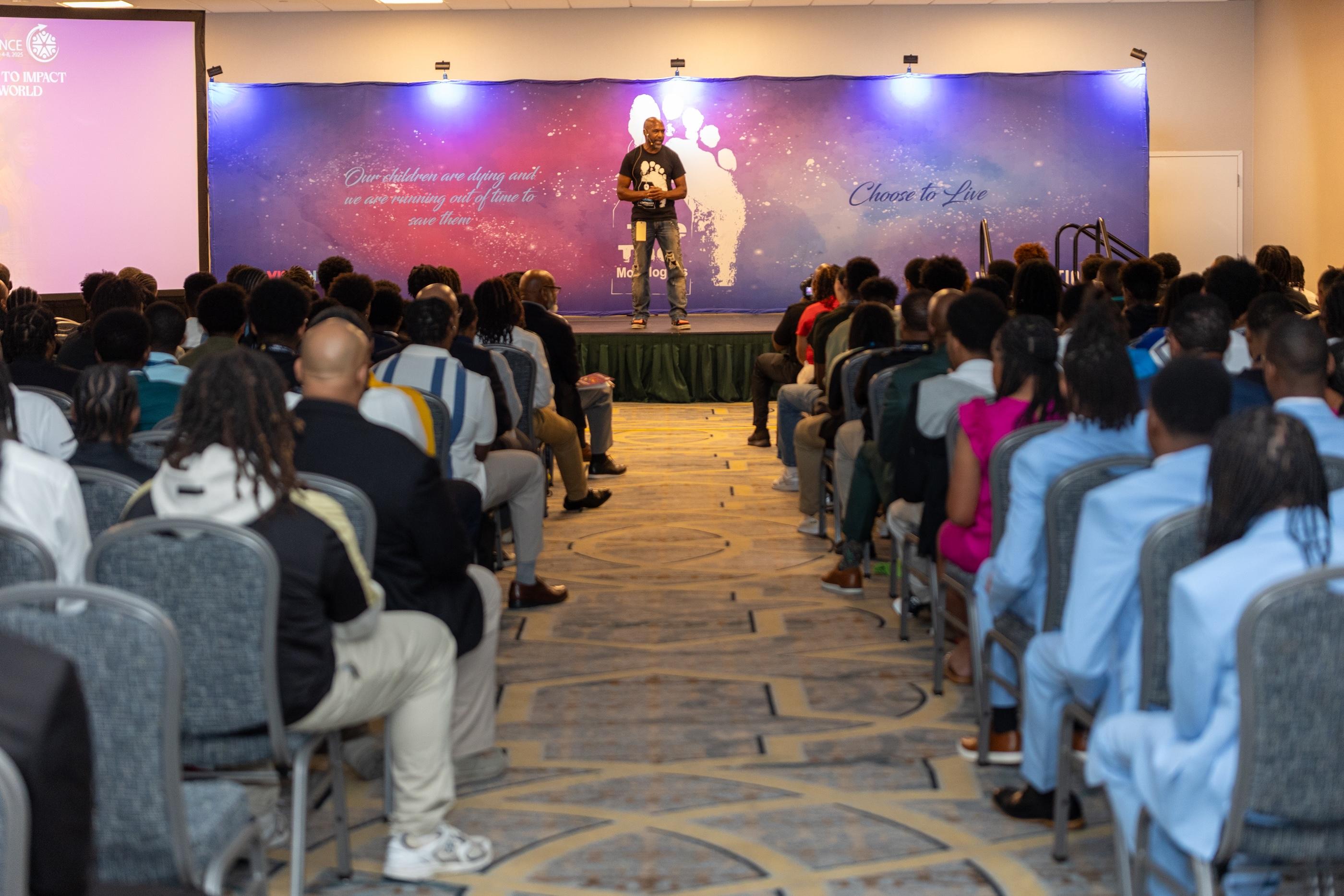 Speaker delivers powerful monologue to seated youth audience during conference session.