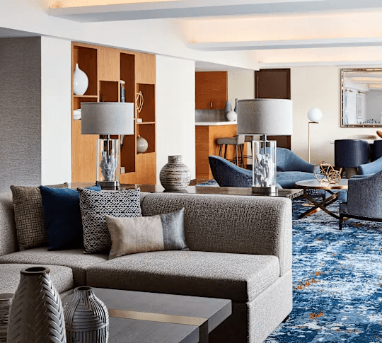 Modern hotel suite living area with sofa, accent chairs, built-in shelving, and contemporary décor.