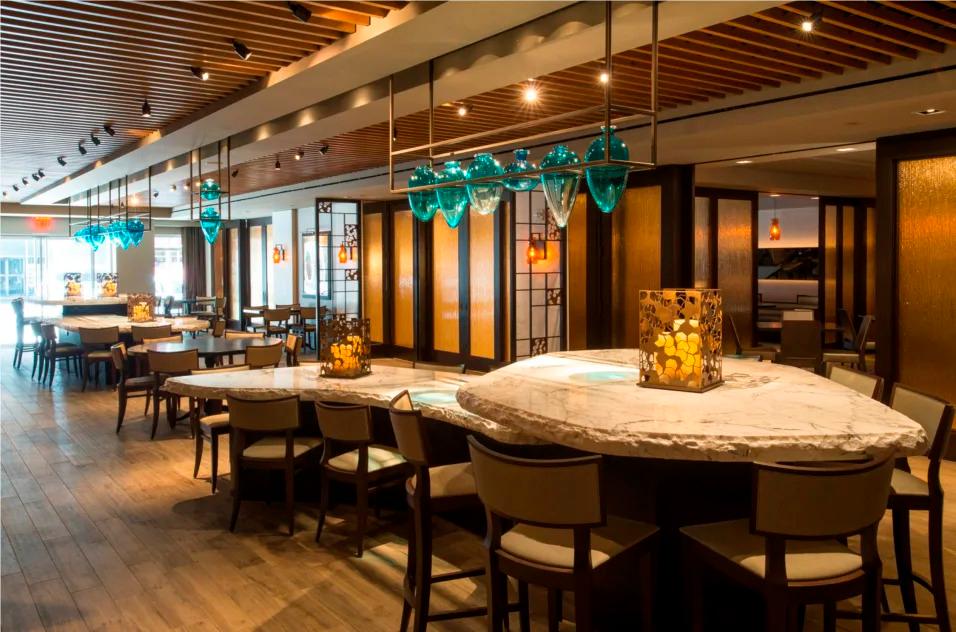 Hotel restaurant with marble bar, warm wood accents, and dining tables