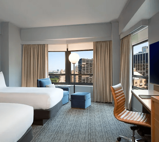 Double queen guest room with desk, lounge seating, and skyline views