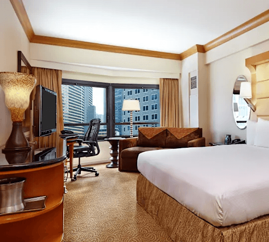 King guest room with city views, desk workspace, sofa, and large windows